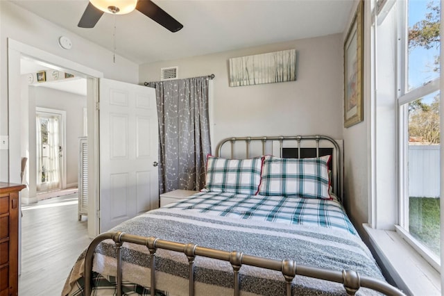 bedroom with multiple windows, wood finished floors, visible vents, and a ceiling fan