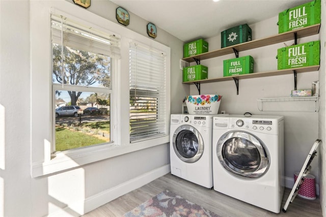 washroom featuring laundry area, baseboards, separate washer and dryer, and wood finished floors