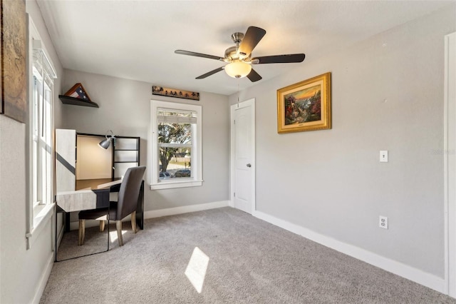 unfurnished office featuring a ceiling fan, carpet, plenty of natural light, and baseboards