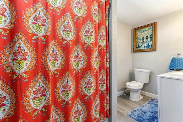 full bathroom featuring a shower with shower curtain, toilet, vanity, wood finished floors, and baseboards