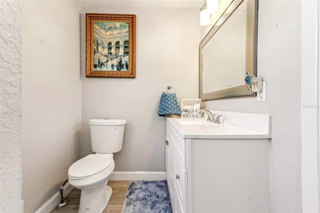 bathroom with toilet, baseboards, wood finished floors, and vanity