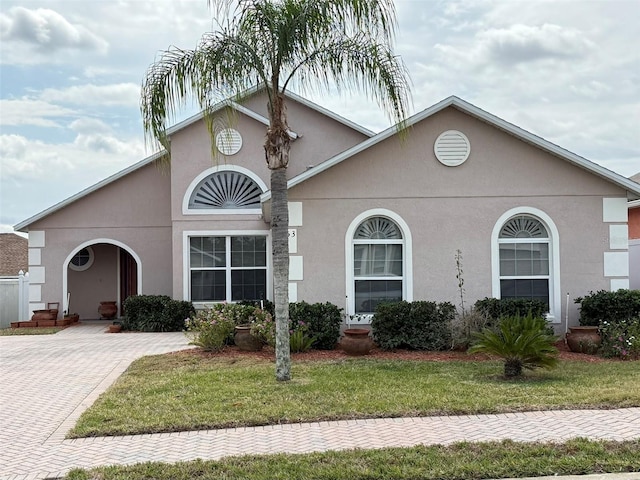 view of front facade with a front lawn, decorative driveway, and stucco siding