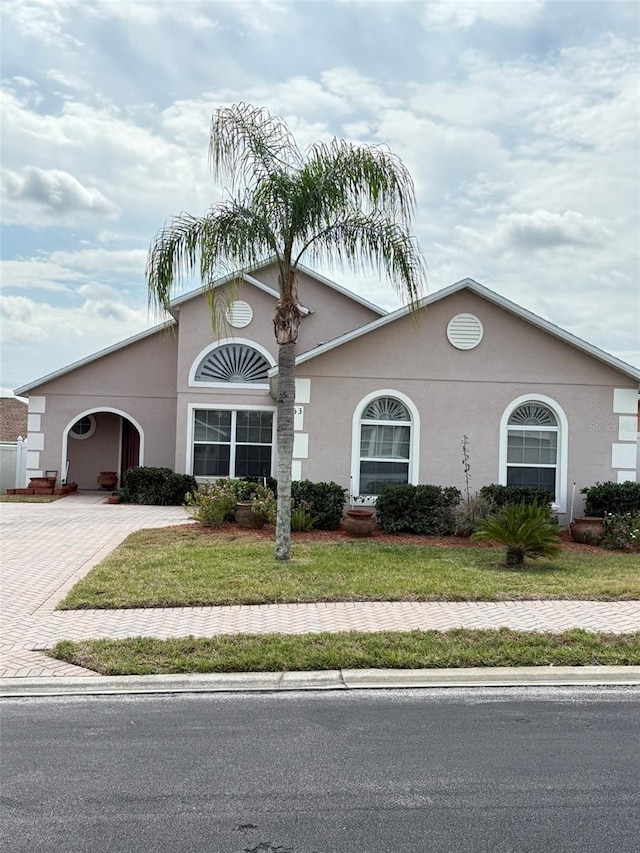 view of front facade with decorative driveway, a front lawn, and stucco siding