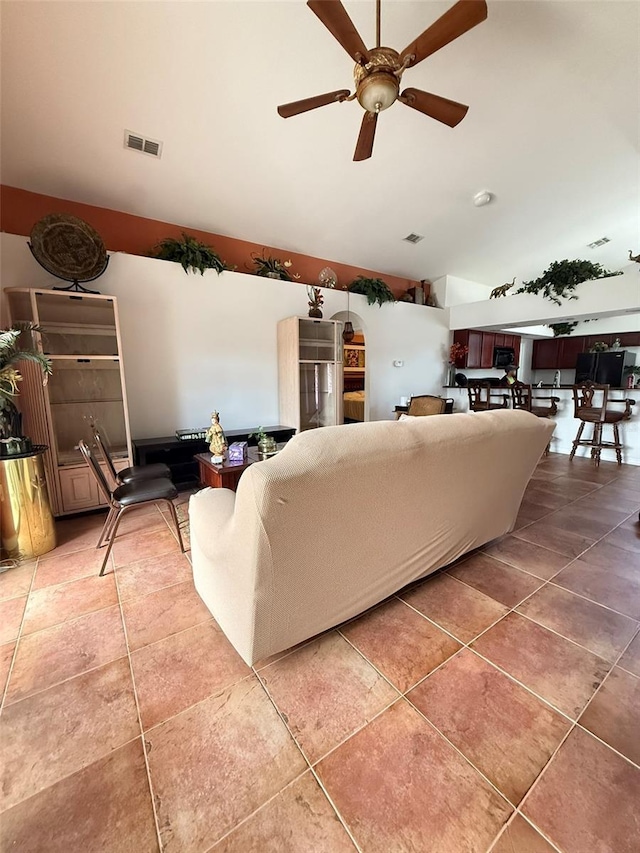 tiled living room with lofted ceiling, ceiling fan, and visible vents