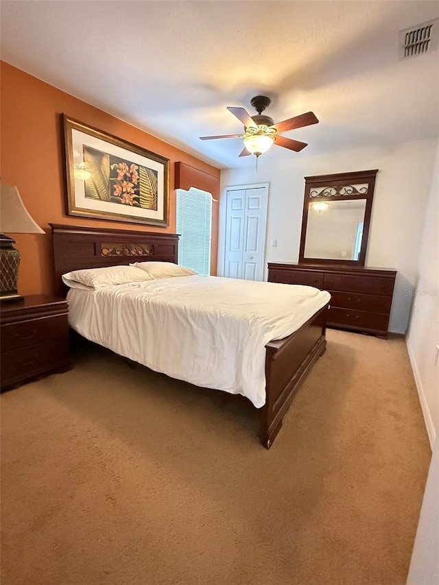 bedroom featuring a closet, visible vents, a ceiling fan, light carpet, and baseboards