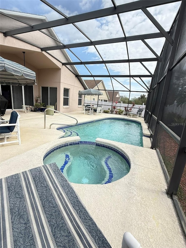 view of pool featuring glass enclosure, a pool with connected hot tub, and a patio