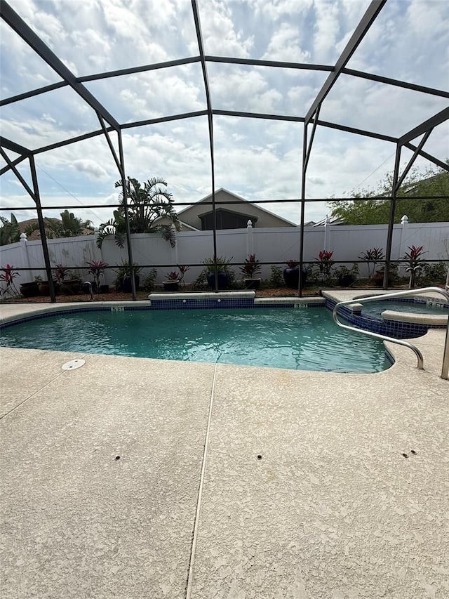 view of swimming pool featuring a fenced backyard, a lanai, and a pool with connected hot tub