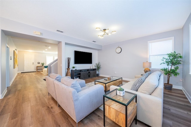 living area with light wood-type flooring, visible vents, and a healthy amount of sunlight