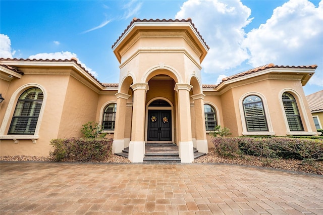 entrance to property featuring a tile roof and stucco siding