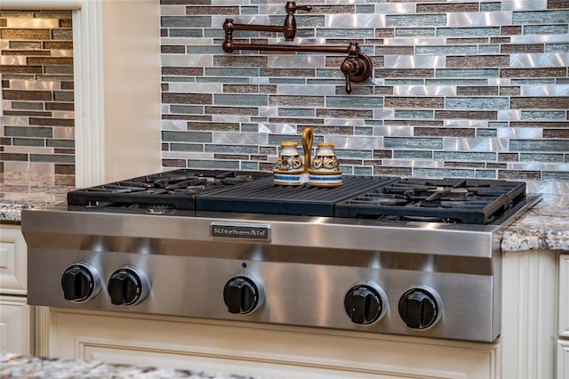 details with light stone countertops, stainless steel gas cooktop, and backsplash