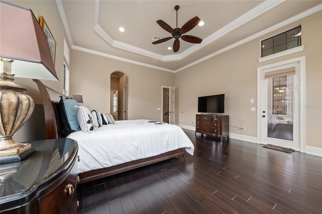 bedroom with crown molding, arched walkways, a raised ceiling, and dark wood-style flooring