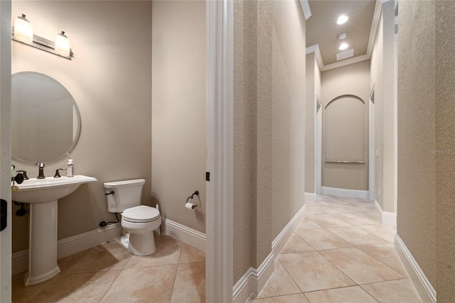 half bath featuring crown molding, recessed lighting, toilet, baseboards, and tile patterned floors