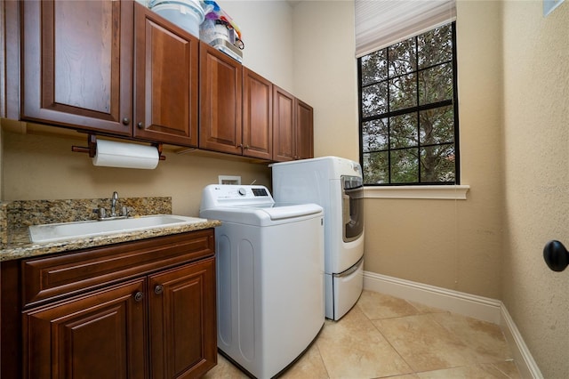 washroom with cabinet space, a sink, washer and clothes dryer, and baseboards