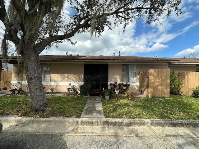 ranch-style house with fence, a front lawn, and stucco siding