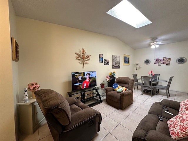 living area featuring light tile patterned floors, vaulted ceiling with skylight, and a ceiling fan