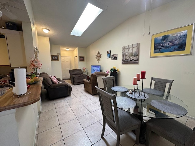 dining area featuring light tile patterned floors and lofted ceiling with skylight