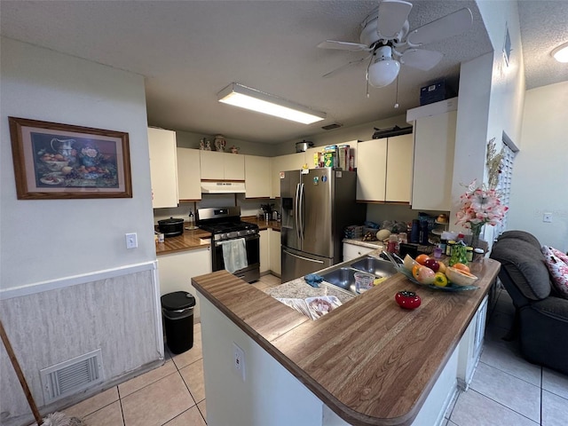 kitchen with light tile patterned floors, visible vents, appliances with stainless steel finishes, a peninsula, and under cabinet range hood