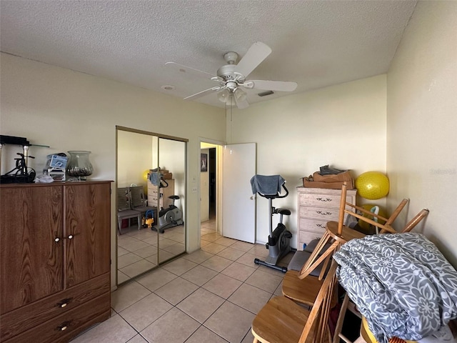 bedroom featuring light tile patterned floors, a closet, visible vents, ceiling fan, and a textured ceiling