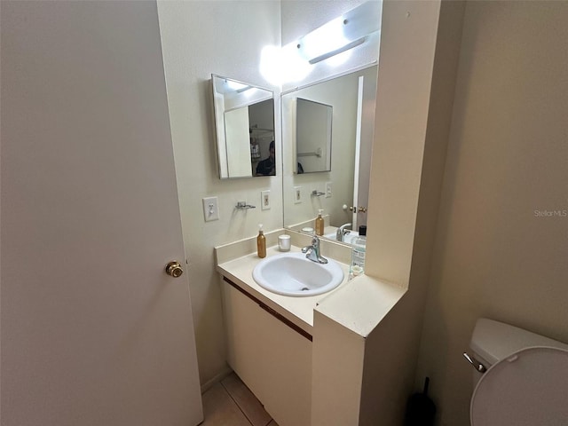 half bath featuring toilet, tile patterned flooring, and vanity