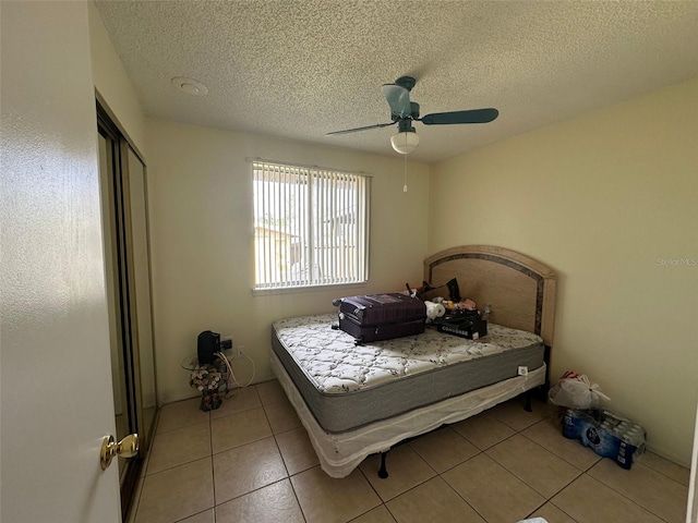 bedroom with a textured ceiling, a closet, a ceiling fan, and light tile patterned flooring