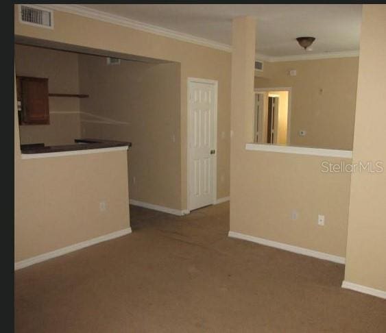 interior space with baseboards, carpet flooring, visible vents, and crown molding