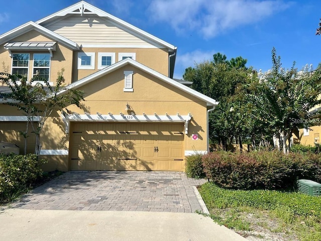 view of front of house with a garage, decorative driveway, and stucco siding