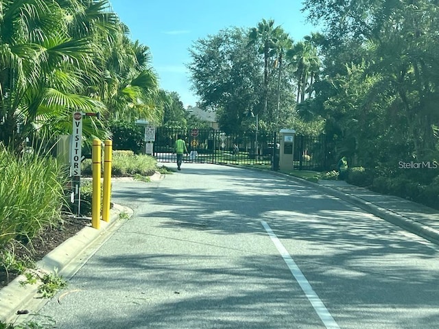 view of road featuring curbs, a gated entry, and a gate