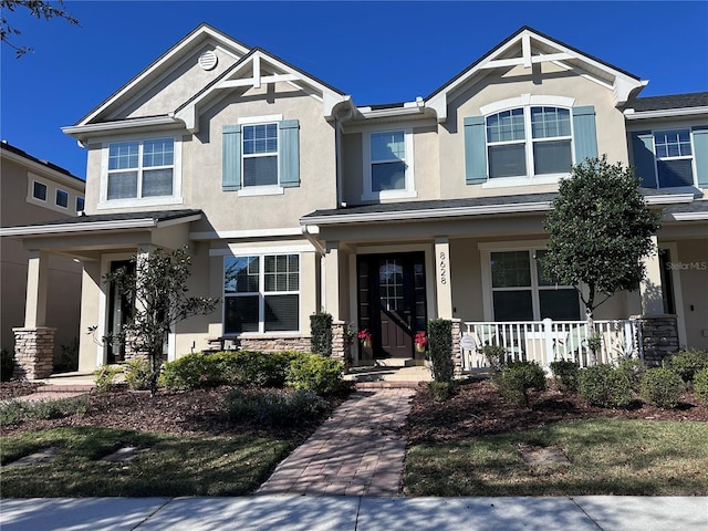 craftsman inspired home featuring stone siding, a porch, and stucco siding