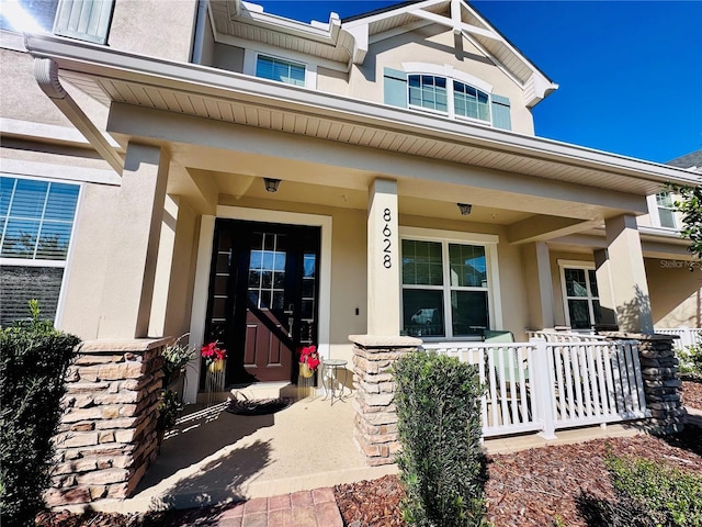 entrance to property featuring covered porch and stucco siding