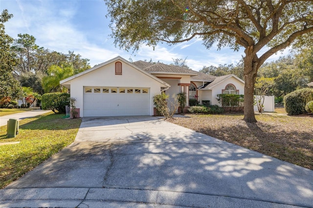 ranch-style house with driveway, an attached garage, and stucco siding