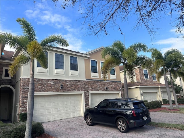 view of front facade with a garage, decorative driveway, and stucco siding