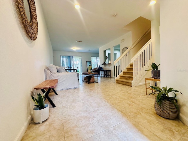 living area featuring stairs, tile patterned flooring, and baseboards