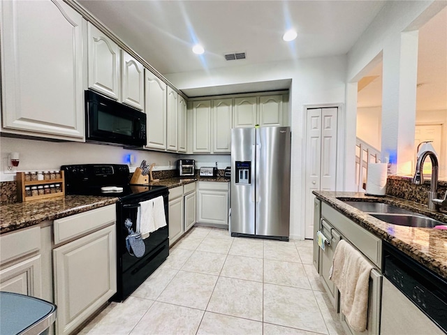 kitchen featuring light tile patterned floors, dark stone countertops, black appliances, a sink, and recessed lighting