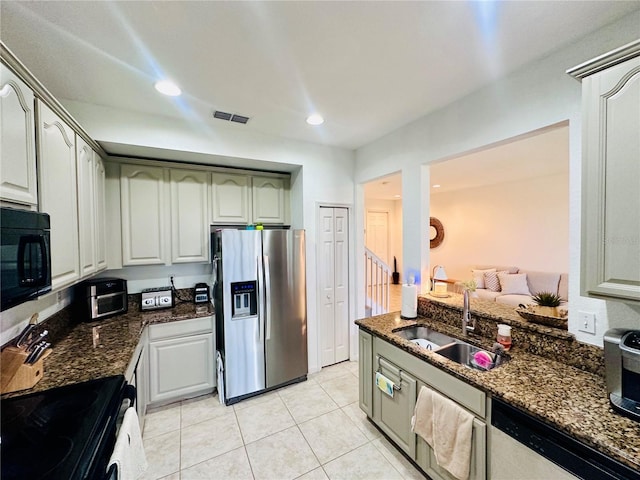 kitchen featuring light tile patterned floors, a sink, visible vents, black appliances, and dark stone countertops