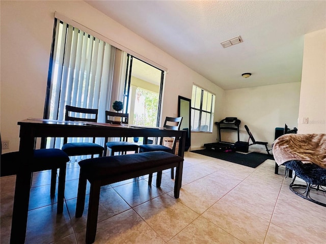 dining area with a textured ceiling, light tile patterned flooring, and visible vents