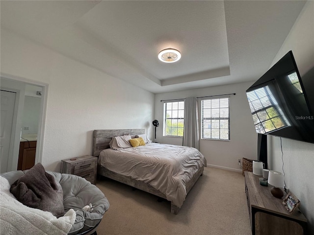 carpeted bedroom featuring a raised ceiling and baseboards