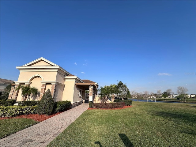 view of front of property featuring a front yard, stone siding, and stucco siding