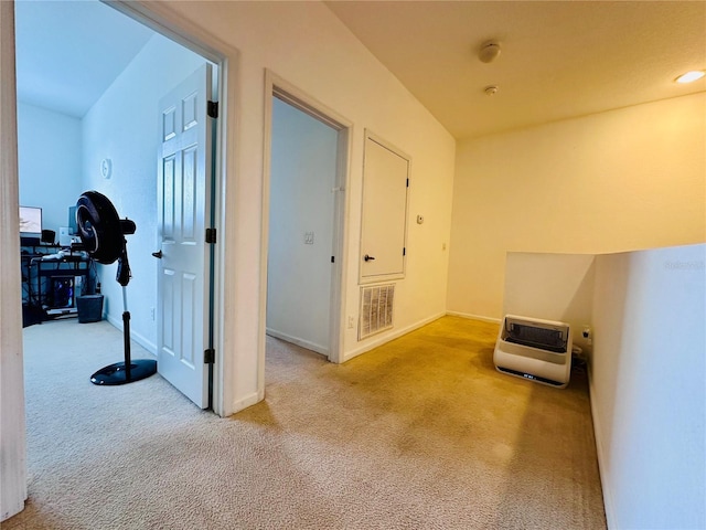 hall featuring baseboards, visible vents, light carpet, and heating unit