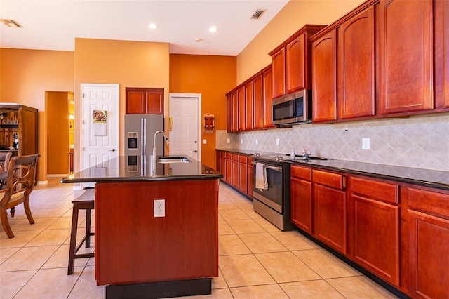 kitchen featuring stainless steel appliances, dark countertops, visible vents, light tile patterned flooring, and a sink