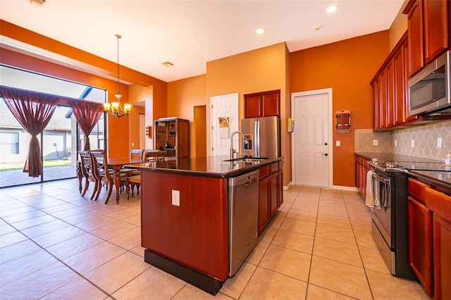 kitchen featuring stainless steel appliances, dark countertops, tasteful backsplash, an inviting chandelier, and a sink