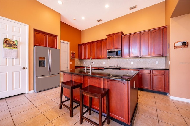 kitchen with light tile patterned flooring, stainless steel appliances, a sink, visible vents, and tasteful backsplash