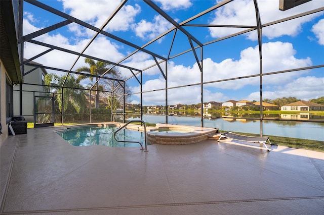 view of pool featuring glass enclosure, a patio area, a pool with connected hot tub, and a water view