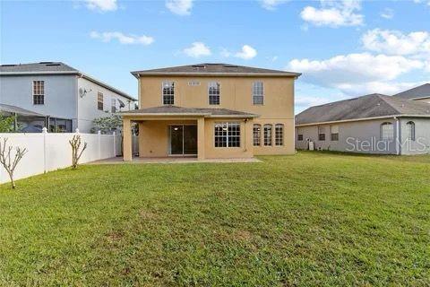 rear view of property featuring stucco siding, a fenced backyard, a patio, and a yard