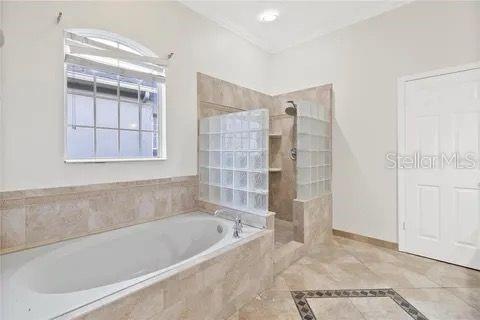 bathroom with baseboards, a bath, and a walk in shower