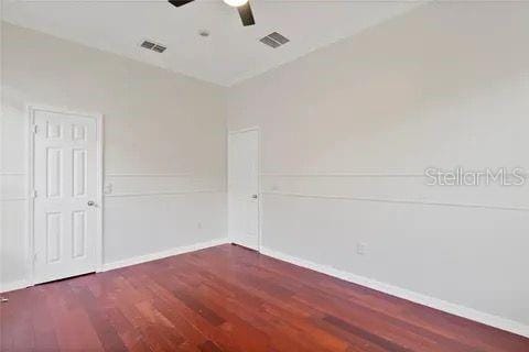 unfurnished room with baseboards, visible vents, and dark wood finished floors