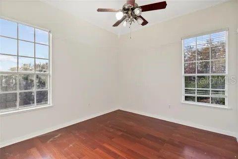 unfurnished room featuring wood finished floors, a ceiling fan, and baseboards