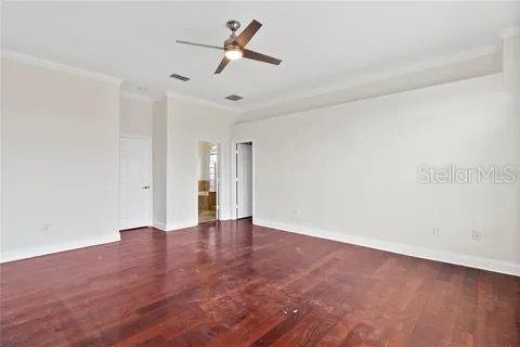 spare room with visible vents, baseboards, dark wood-style flooring, and crown molding