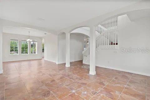 spare room featuring baseboards, stairway, arched walkways, and a chandelier