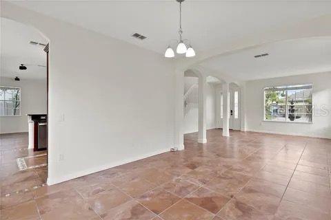 spare room featuring a wealth of natural light, arched walkways, visible vents, and an inviting chandelier