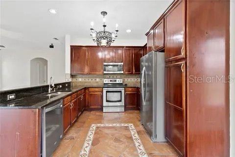 kitchen with stainless steel appliances, a peninsula, a sink, decorative backsplash, and pendant lighting